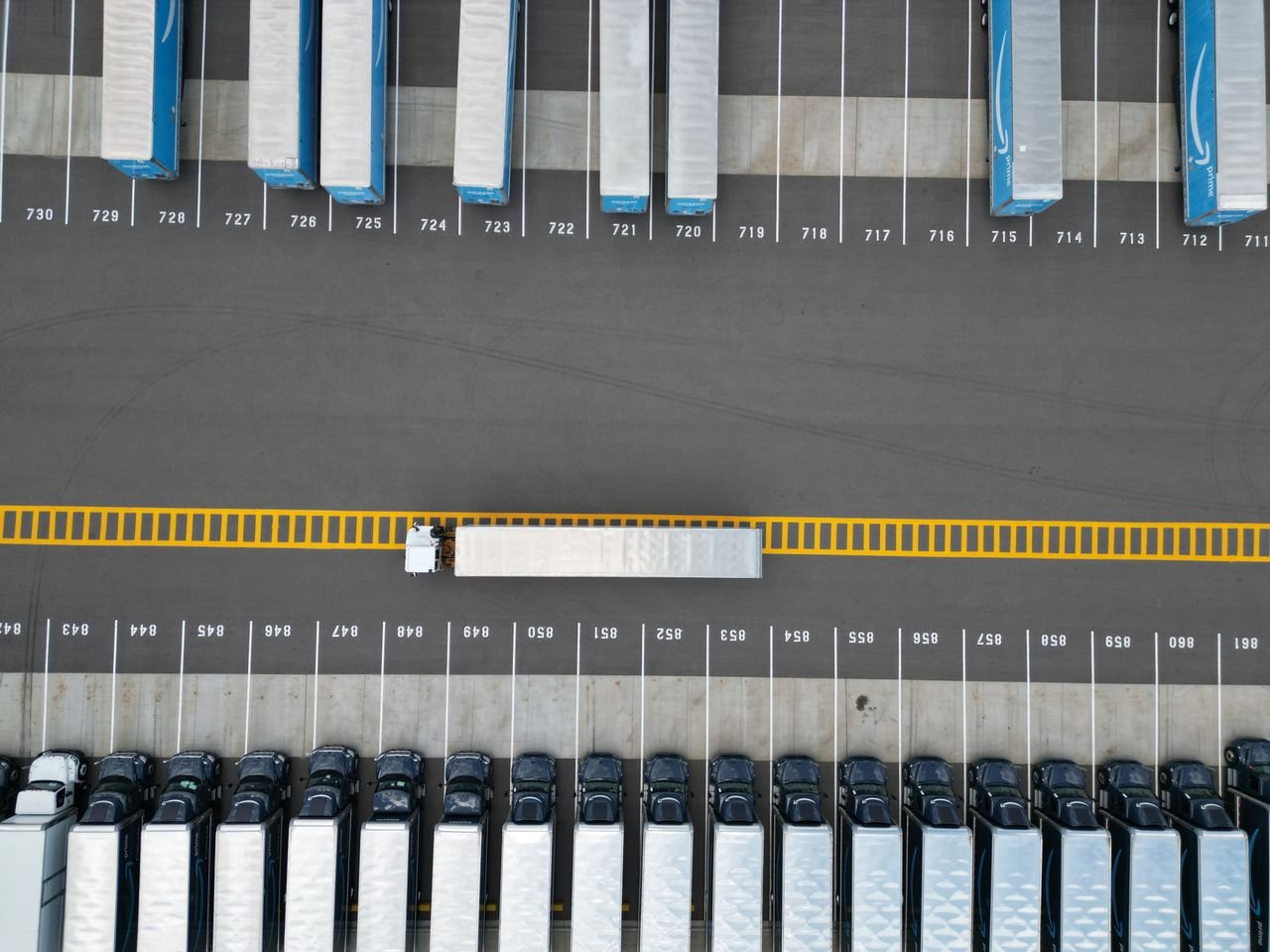 Top-down aerial image of truck trailers parked in a lot with distinct yellow markings.